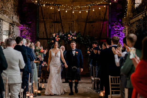 Couple walk back down the aisle at Pratis Barns as guests clap